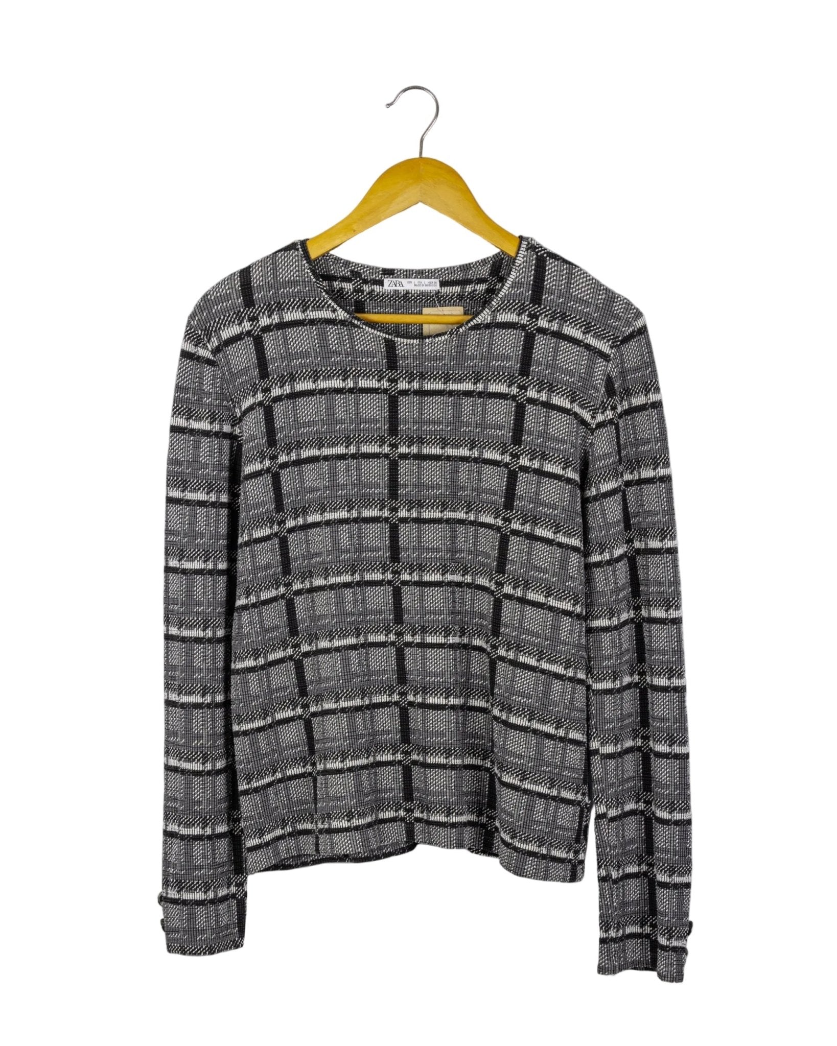Polo manga larga Zara, de tela acanalada de cuadros grises y negros, con botones plateados en los puños