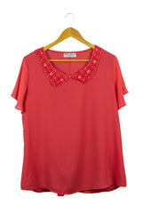 Blusa fucsia de gasa, cuello camisero redondeado con perlitas fucsias y manga corta con vuelos.